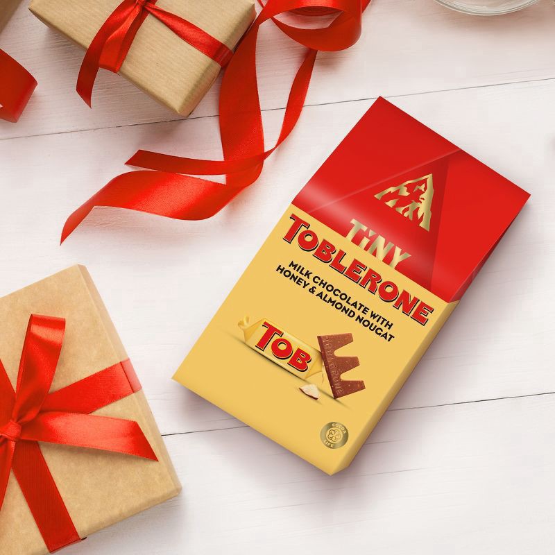 slide 9 of 14, TOBLERONE Tiny Milk Chocolate Bars with Honey and Almond Nougat, 1 Gift Bag (18 Pieces), 5.07 oz